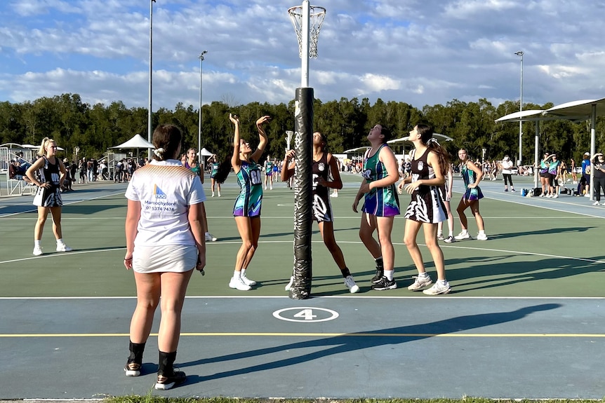 A netball referee watches the players kicking a goal.
