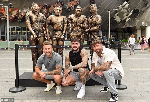 Three of the 'four guys in jeans' crouched in front of their new statue to take some promotional photos.