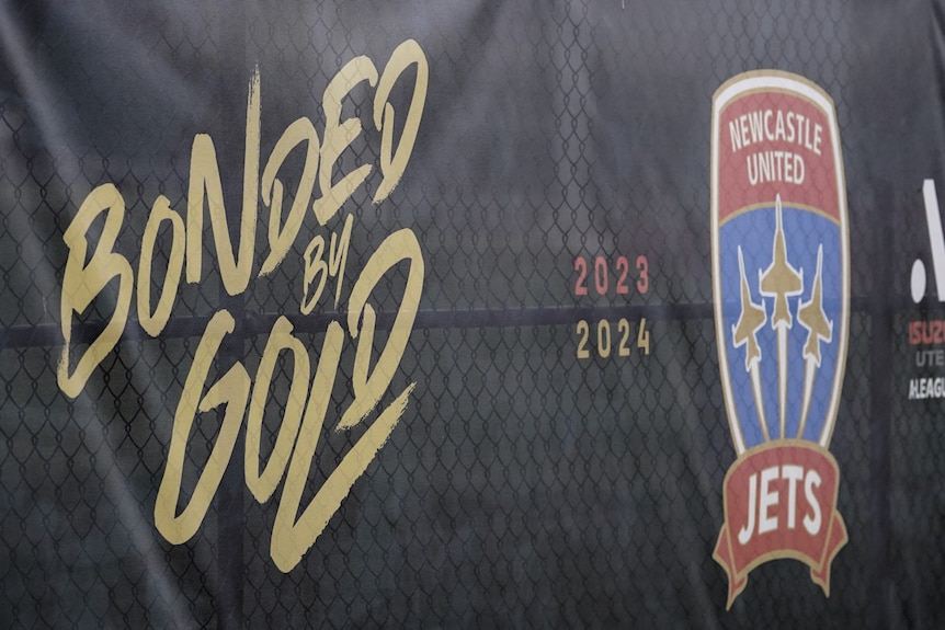 A banner with the Newcastle Jets logo at the gate of a sports ground.