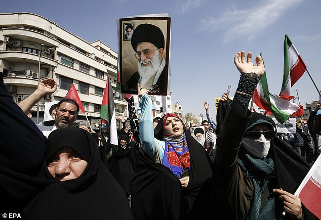 An Iranian woman (center of photo) holds a portrait of Iranian Supreme Leader Ayatollah Ali Khamenei as others wave Iranian and Palestinian flags during an anti-Israel demonstration in Tehran.