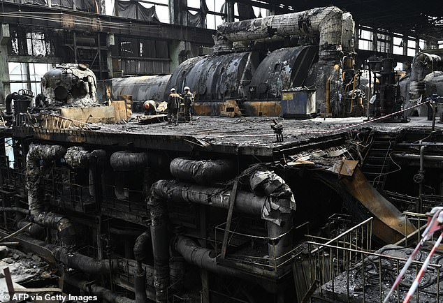 Workers clear debris in a turbine hall filled with charred equipment at a power plant of energy provider DTE.