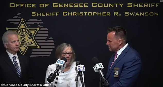 The victim's daughter (center) became emotional when the video was shown at a news conference also attended by Genesee County Sheriff Chris Swanson (right) and prosecutor David Leyton (left).