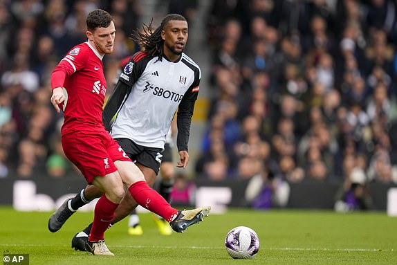 Liverpool's Andrew Robertson, front, duels for the ball with Fulham's Alex Iwobi during the English Premier League football match between Fulham and Liverpool at Craven Cottage stadium, London, Sunday April 21, 2024. ( AP Photo/Kirsty Wigglesworth)