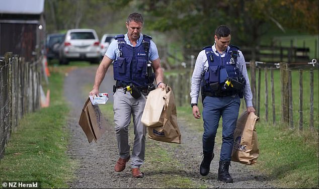 Police are pictured carrying bags of evidence at the property where the retired couple died.