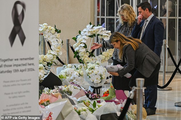 People lay flowers at a memorial set up inside the Bondi Junction Westfield shopping center to honor the victims of the Cauchi stabbing.