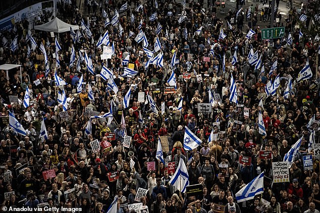 Netanyahu faces considerable pressure at home from his citizens and within his own government.  (Pictured: Thousands of people carry Israeli flags and chant anti-government slogans as they stage a protest demanding Benjamin Netanyahu's resignation)