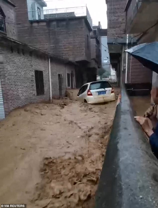 A vehicle was seen being swept away in thick, muddy floodwaters as helpless onlookers watched in horror.
