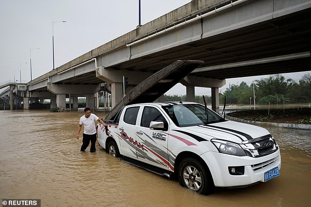 Resident Huang Jingrong cleans his car with a boat tied to the back after the weather disaster.