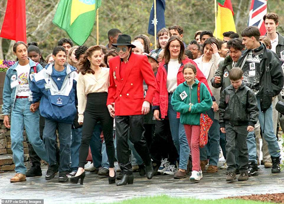 Michael Jackson is seen holding hands with his ex-wife Lisa Marie Presley as they walk with children at his Neverland Ranch, welcoming them during a three-day World Children's Summit in 1995.