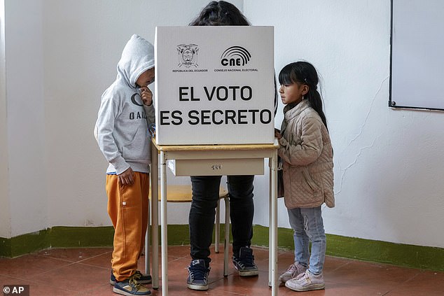 Children next to a voter marking questions on the ballot for a referendum proposed by President Daniel Noboa to support new security measures aimed at ending the criminal gangs that fuel the escalation of violence.