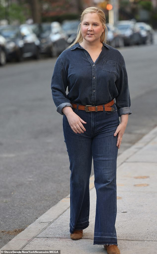 The fun lady was dressed in a dark denim button-down shirt with rolled-up sleeves and a pair of dark denim jeans with frayed hems. Her waist was highlighted with a dark brown belt and she wore coordinating dark brown boots.