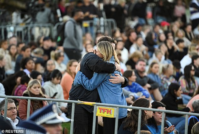 People are seen hugging each other at a vigil on Bondi Beach for the victims on Sunday night.