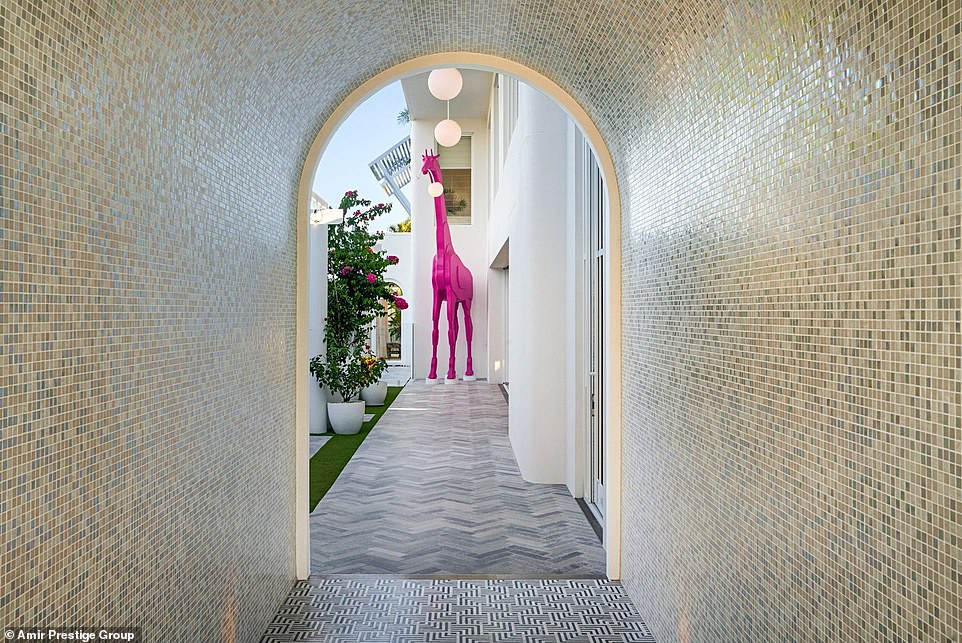 Visitors enter the unique house through an arched mosaic tunnel only to be greeted by a five-metre-tall bright pink giraffe, playfully designed to look like it has gnawed on one of the hanging lights from the ceiling.