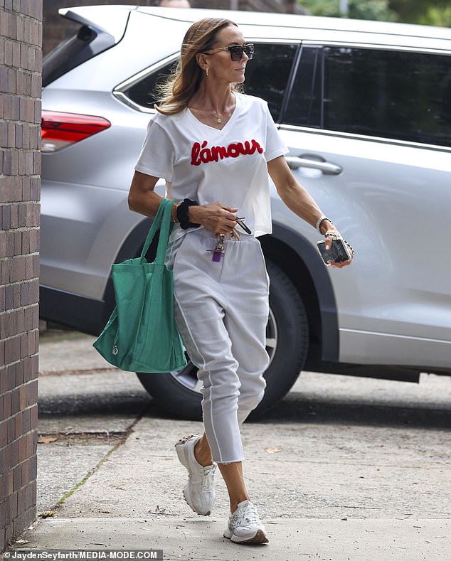 The former WAG, 42, looked effortlessly chic in a white 'L'amour' top and matching white trousers that highlighted her slender figure and flawless tan.