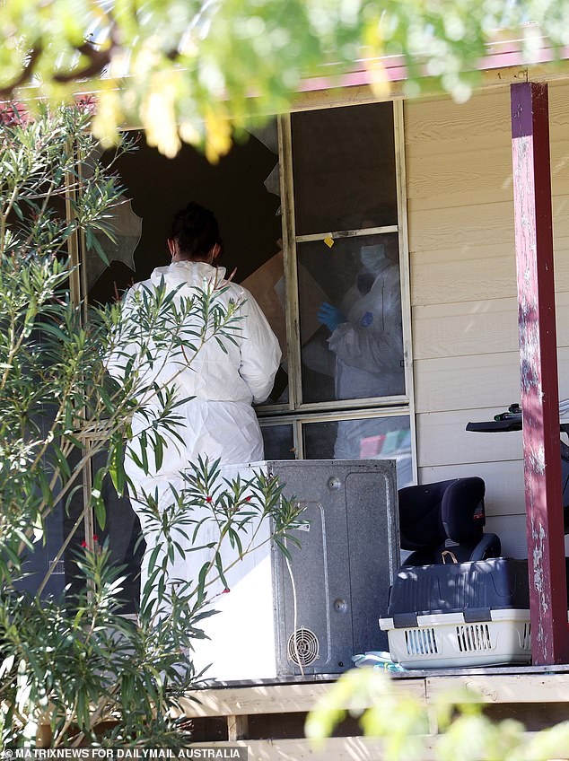 A forensic team is seen looking through a broken window at the front of the ramshackle house.