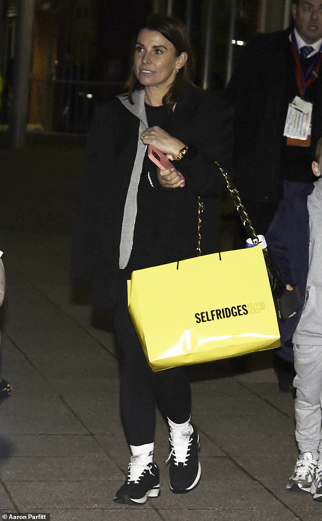 She looked low-key in a simple black coat, tight leggings and trainers while carrying a large Selfridges bag.