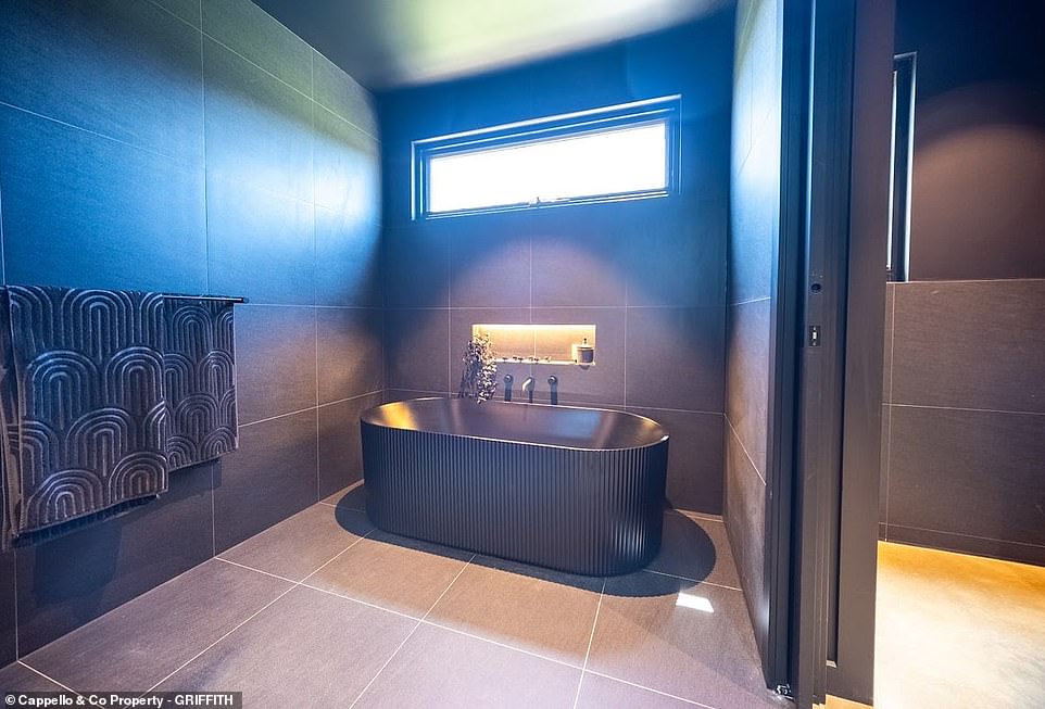 The bathroom has mirrored cabinets, huge his and her walk-in closets, and a unique bathtub with all-black surrounds.