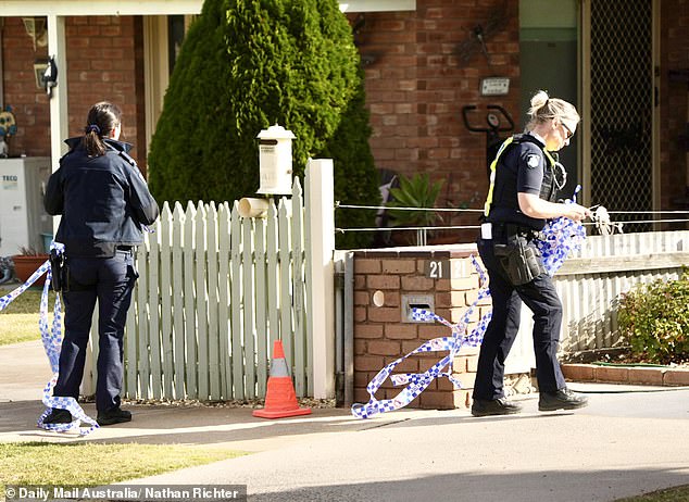 Police officers are seen removing crime scene tape at the home Wednesday afternoon.