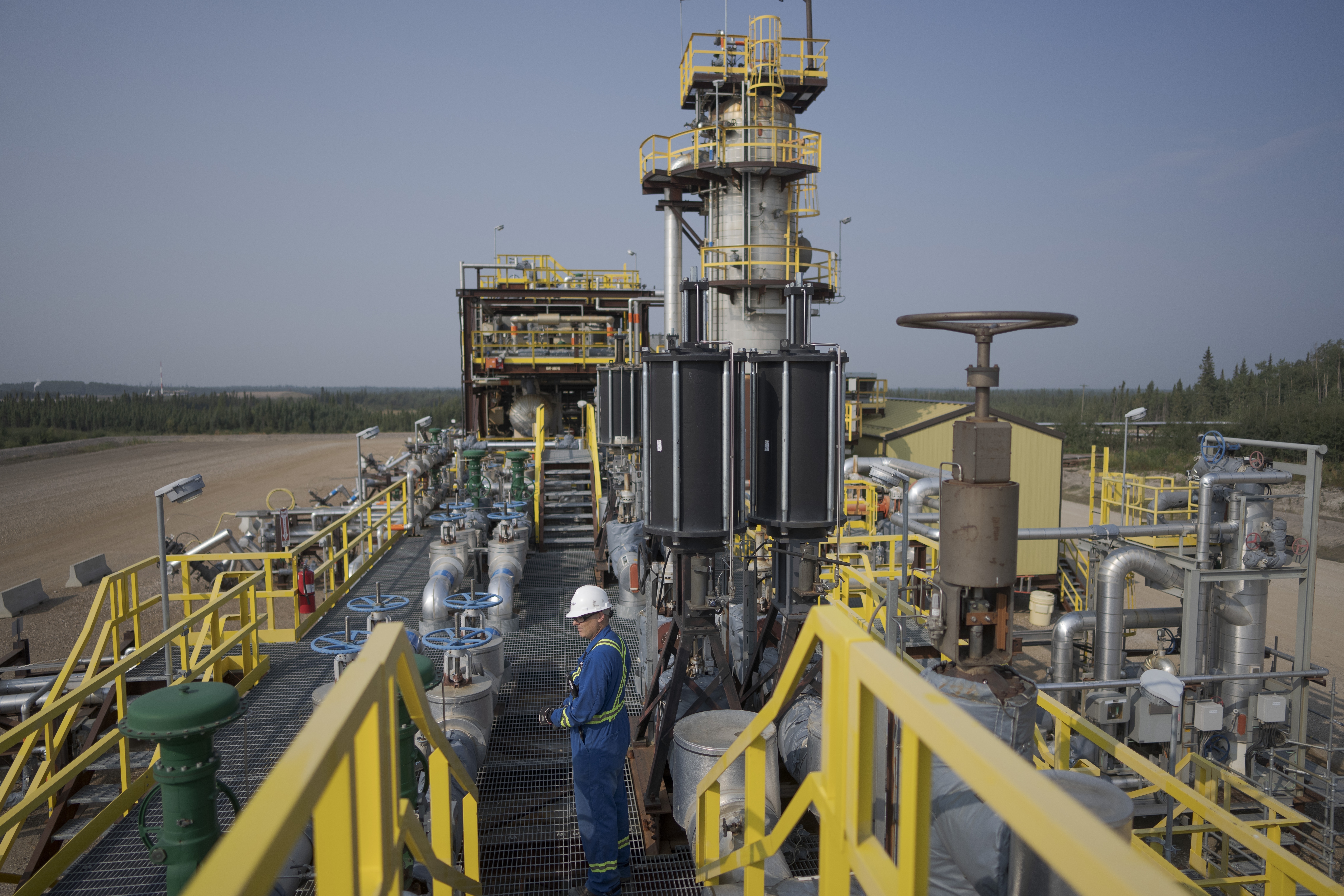 A worker stands on a steam-assisted gravity dewatering platform at Cenovus' Sunrise oil facility.  In Canada, support for carbon pricing has eroded as high interest rates and cost-of-living concerns have taken over.