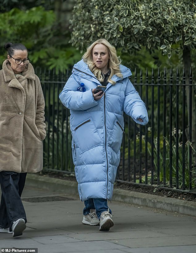 Rebel wrapped in a long light blue quilted coat while walking through the capital