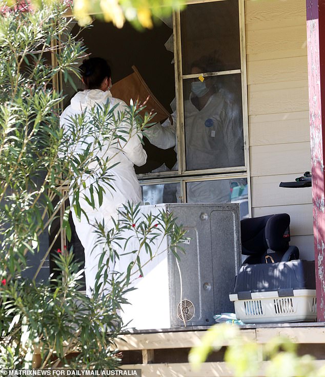 Forensic investigators are pictured at Molly Ticehurst's home on Tuesday. The windows were broken