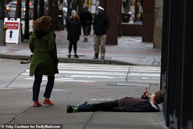 Synthetic opioid users often lie on the streets lost in the throes of substance use.  Pictured: A man suspected of being under the influence of drugs in Seattle