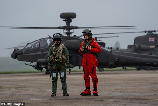 A pilot prepares an Apache helicopter as a fleet of more than a dozen helicopters prepares to take off.