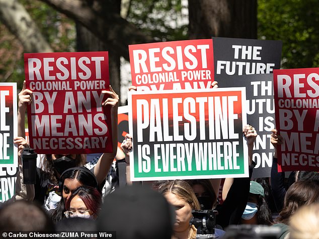 A group of New York University students, faculty and supporters hold signs to liberate Palestine during a rally in Washington Square Park.