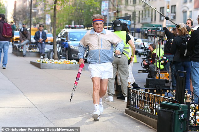 He had an umbrella in one hand as he walked quickly down the sidewalk with cameras pointed at him.