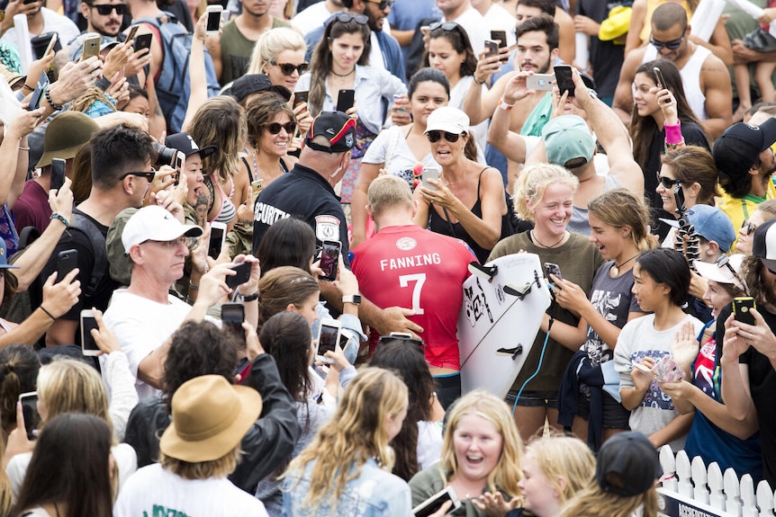 Mick Fanning makes his way through the crowd of fans on the beach