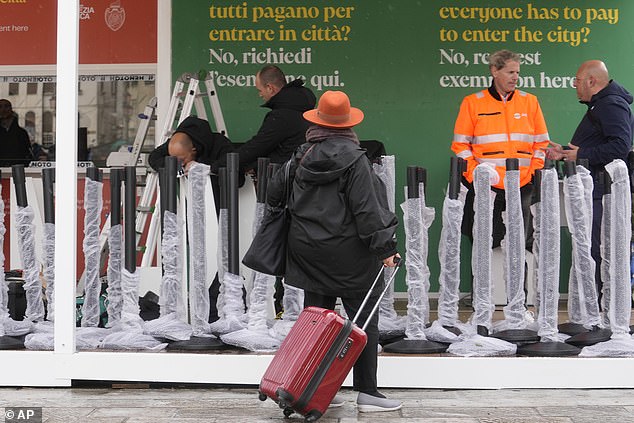 Workers prepare tourist tax checkout counters outside the main train station in Venice, Italy, Wednesday, April 24, 2024.