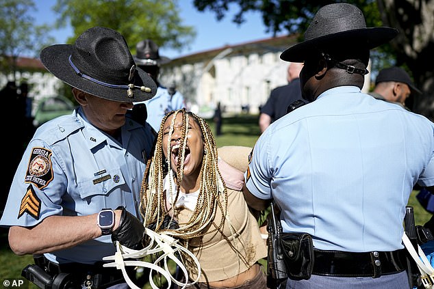 Another protester is seen screaming as two Georgia State Patrol officers hold her arms.  One of the officers (left) is seen holding a bundle of white zip ties.