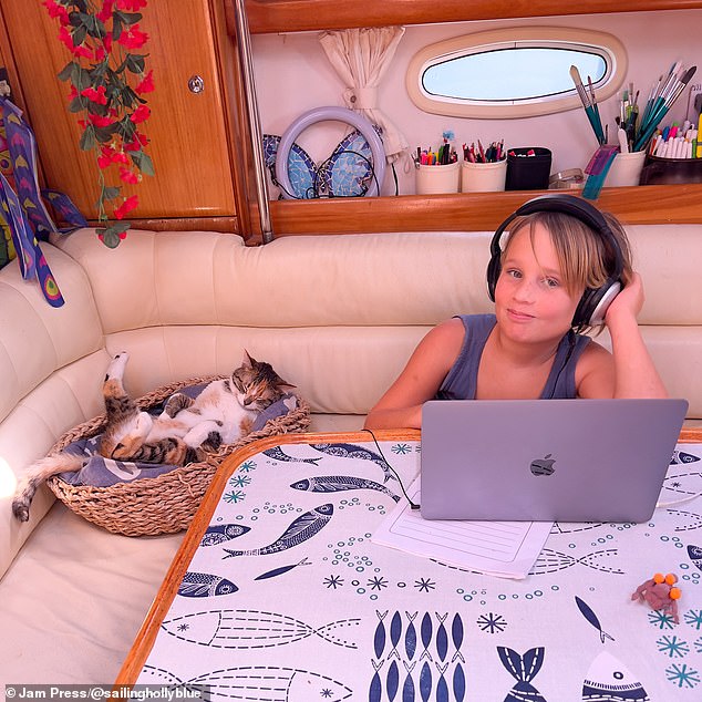 Her son Noah enjoys time with one of the family cats in his beautiful room while doing his schoolwork on a laptop.
