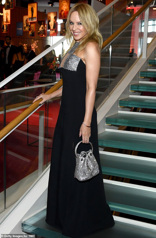 Minogue completed the ensemble with a jeweled bracelet and matching ring, and carried a silver drawstring clutch with jewels on a hoop handle.