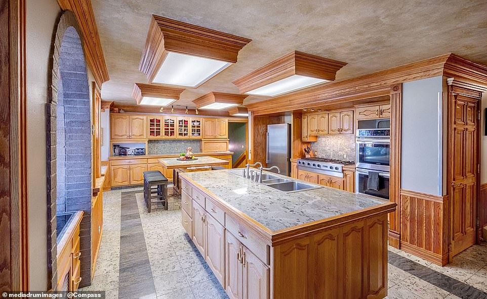 The kitchen is fully equipped for a gourmet chef and has two islands. The space is decorated with wood and marble throughout.