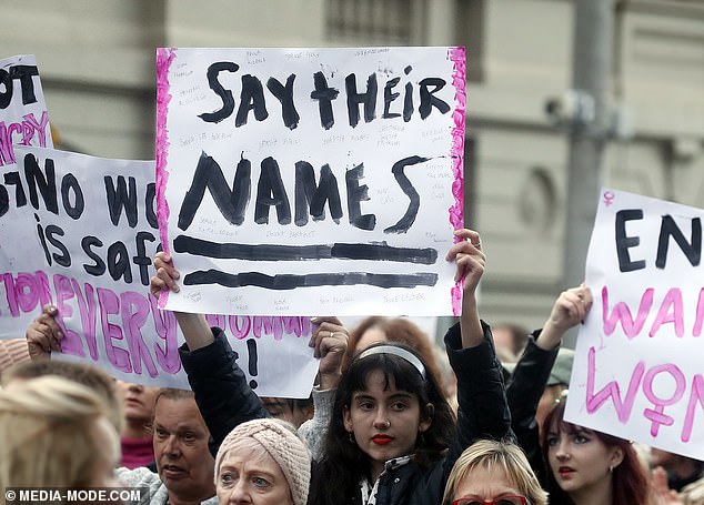 A woman holds a sign that says 