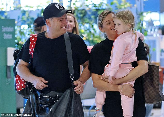 Karl carried his essentials in a large checkered canvas bag, while he also carried his daughter's red sequined backpack over one shoulder.