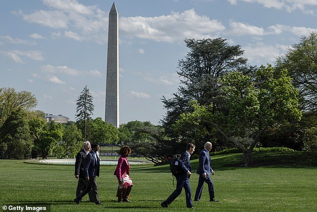 President Joe Biden walks on the South Lawn after landing on Marine One with senior members of his staff, including Bruce Reed and Karine Jean-Pierre.