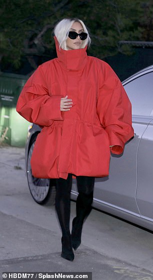 The SKIMS founder, 43, showed off her impeccable sense of style in an oversized red coat, stockings and black stilettos.
