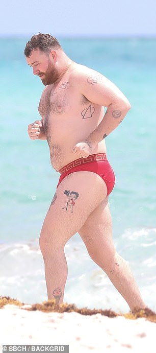 The singer, 31, showed off her tattooed skin while going shirtless and wearing tiny red Versace speedos.