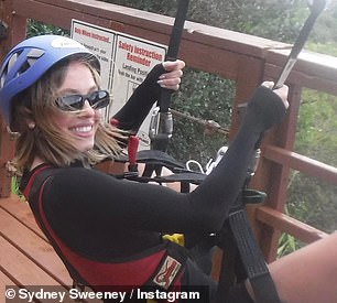 Sweeney smiled at the camera before setting off on his journey above the treetops wearing a black long-sleeved suit and shorts with a red vest and a blue crash helmet.