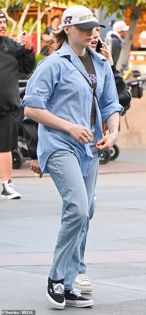 Moretz tucked the T-shirt into faded jeans with a Disney pin on the pocket, with black and white sneakers.