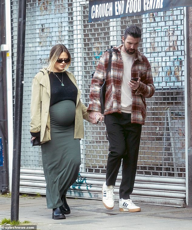 The mother-to-be looked radiant in a short black sweater and a long tight khaki skirt, which she paired with a beige trench coat.