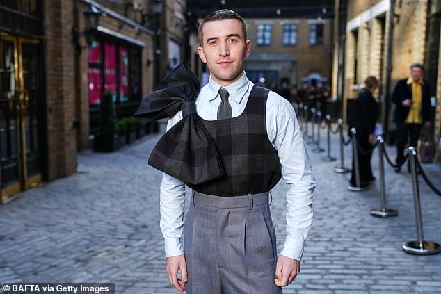 It's a Sin star Callum Scott Howells wore a quirky bow vest and gray trousers as he posed before entering.