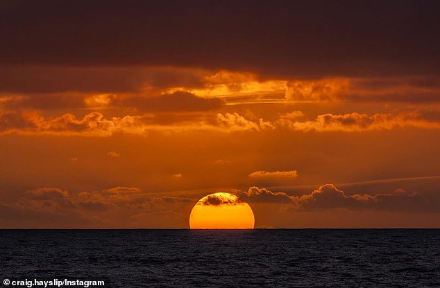 In the first photo Hayslip posted, a portion of the sun was seen setting below the horizon as dark orange clouds loomed overhead.