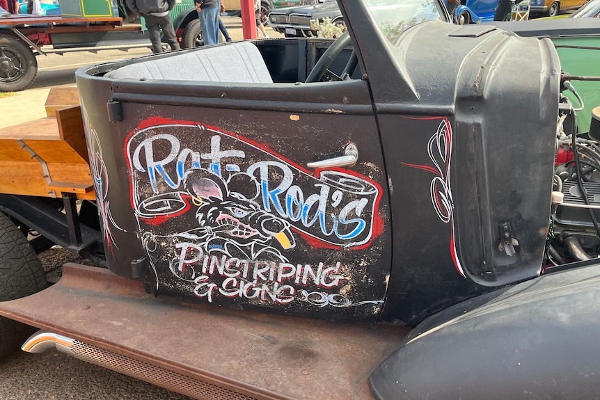 A car door has the words Rat Rod painted on it.