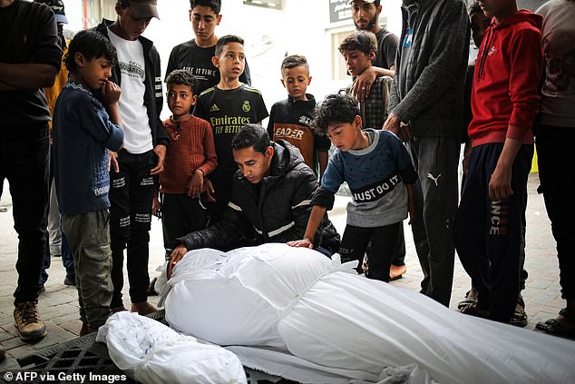Mourners stand near the bodies of an adult and a child killed in an overnight Israeli bombing, outside a hospital morgue in Rafah, southern Gaza Strip, April 27, as conflict between Israel and the militant group Hamas.