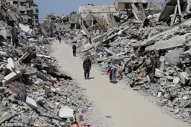 Palestinians walk past the ruins of houses and buildings destroyed during Israel's military offensive (file photo)