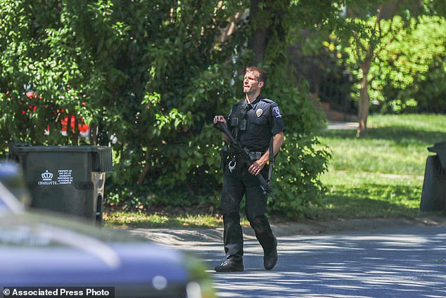 A Charlotte Mecklenburg police officer carries a gun while walking through the neighborhood where an officer-involved shooting occurred in Charlotte.