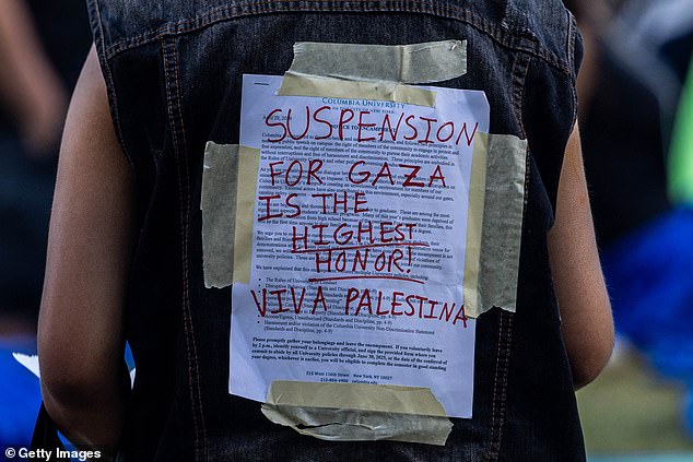 A protester carries the university disciplinary notice covered for support for Palestinians in Gaza at Columbia University.